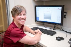 A woman sitting at a desk with a computer screen.