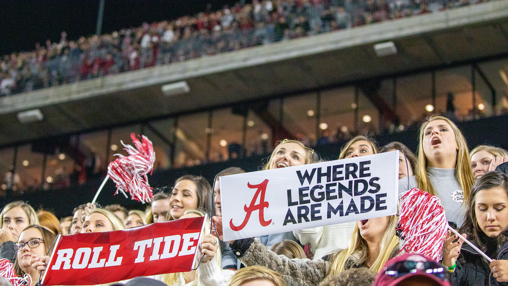 UA students hold signs in the stands of a football game.
