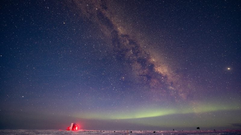 A well-lit structure on the ice with a starry sky and light visible above.
