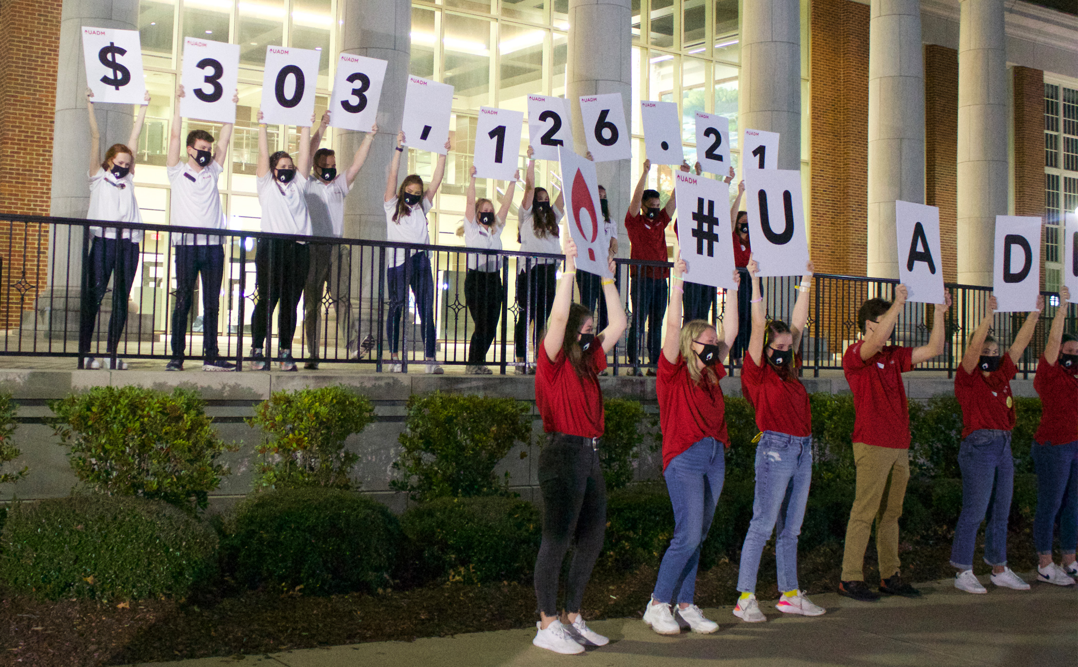 A group of students holding signs that reveal the total of money raised over the past year.