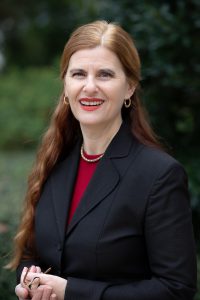 A portrait of a woman in a suit outside.