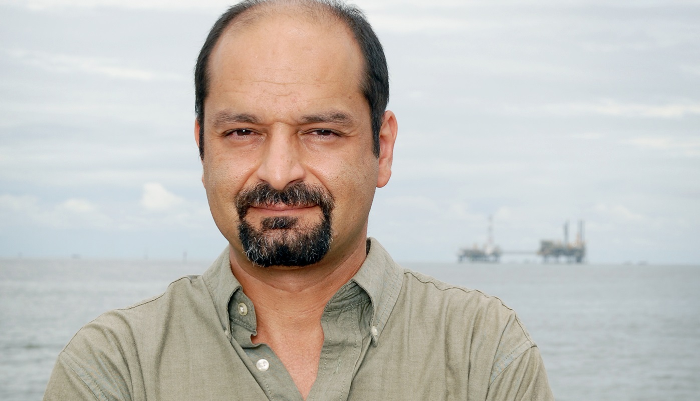 A man poses for a portrait in front of a bay.