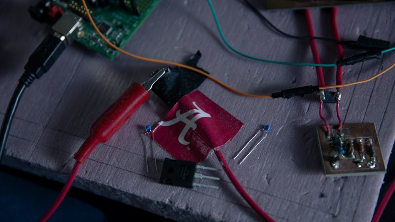 Circuits and electrical wires are connected with UA-themed tape.