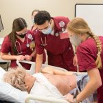 Four nursing students training on a simulator in a lab