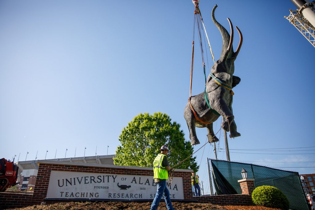 the bronze elephant statue hovers over the ground via crane in front of Bryant Denny stadium