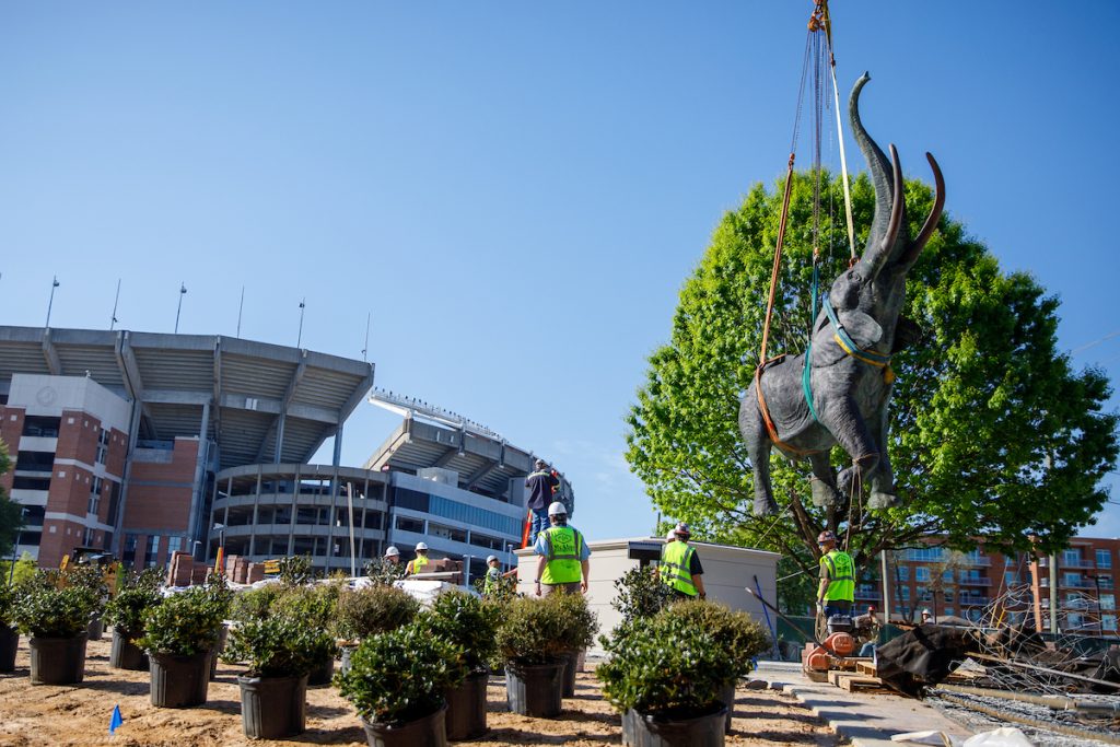 the bronze elephant statue hovers over the ground via crane in front of Bryant Denny stadium