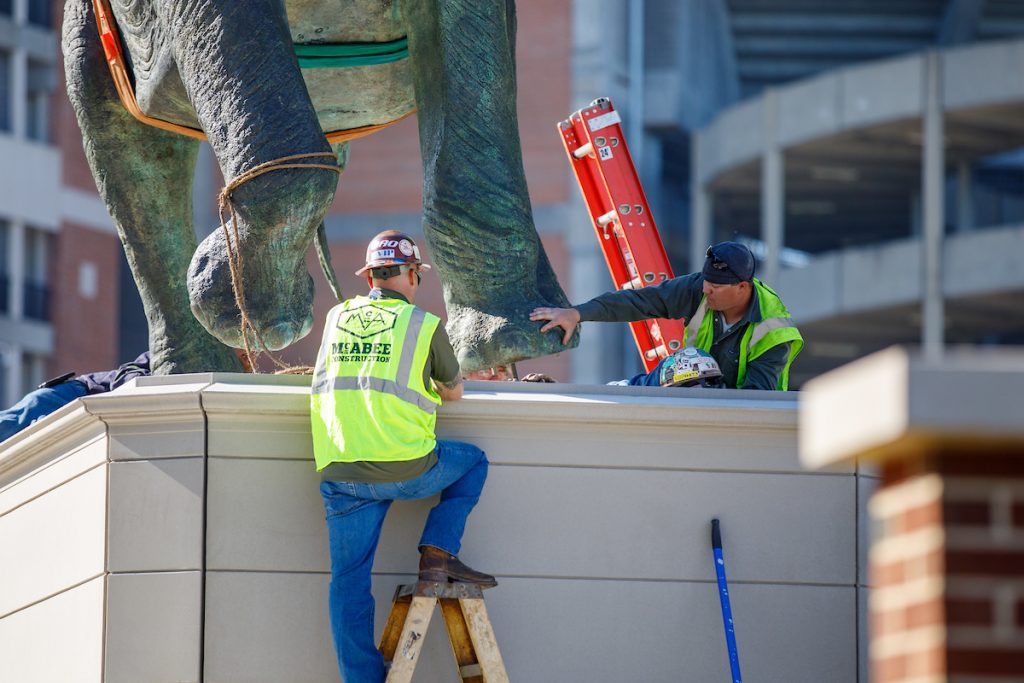 workers install the Tuska statue on its pedestal