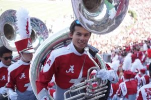 A college student holding the tuba.