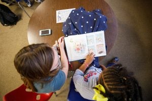 A young student reading a book to a college student