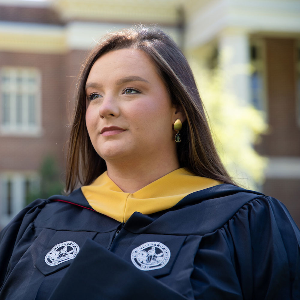 Destiny Mcfall wearing graduation gown looks into the distance