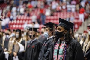 Students sit socially distant, wearing masks at commencement.