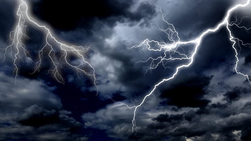 a bolt of lighting in the sky set against dark storm clouds