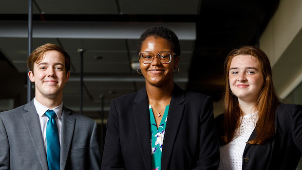 Three people pose for a photo inside a building at The University of Alabama.