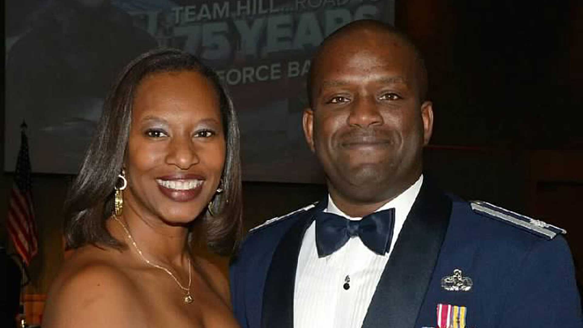 Smiling at the camera is a man and a woman, dressed in a military uniform and formal gown.