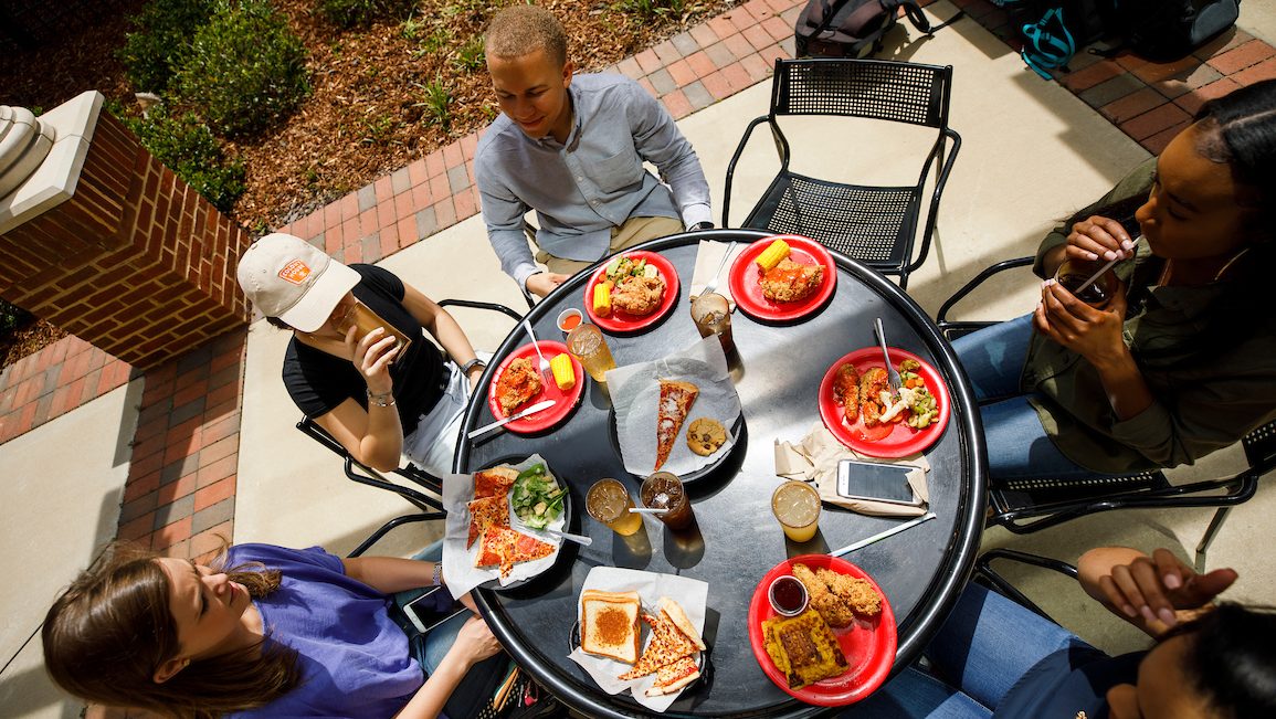 a view of six students eating on the terrace at Lakeside Dining Hall