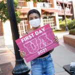 A female student poses for the first day of classes while wearing a mask.