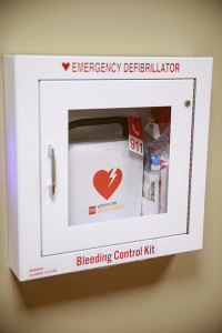 An AED cabinet hangs on a wall.