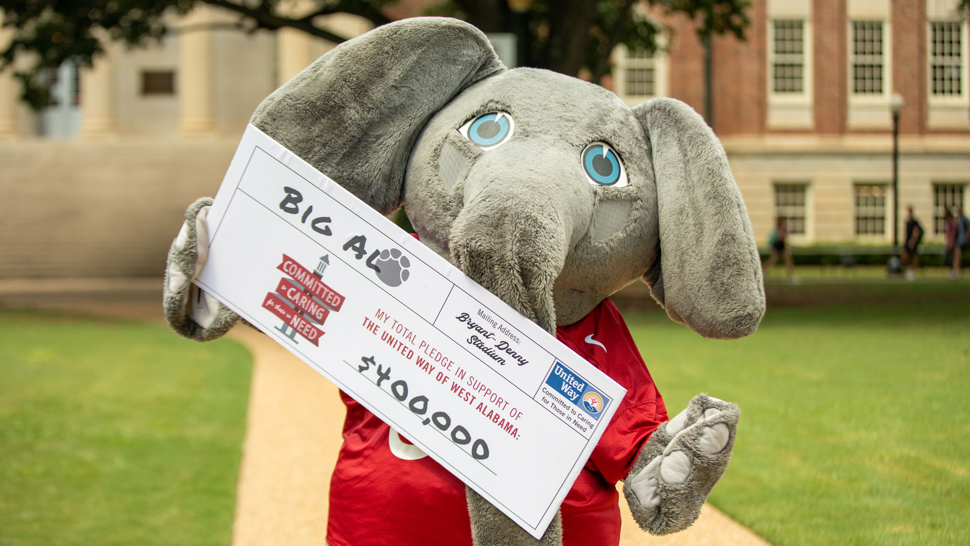 Big Al holds a giant pledge card for the United Way that reads "$400,000