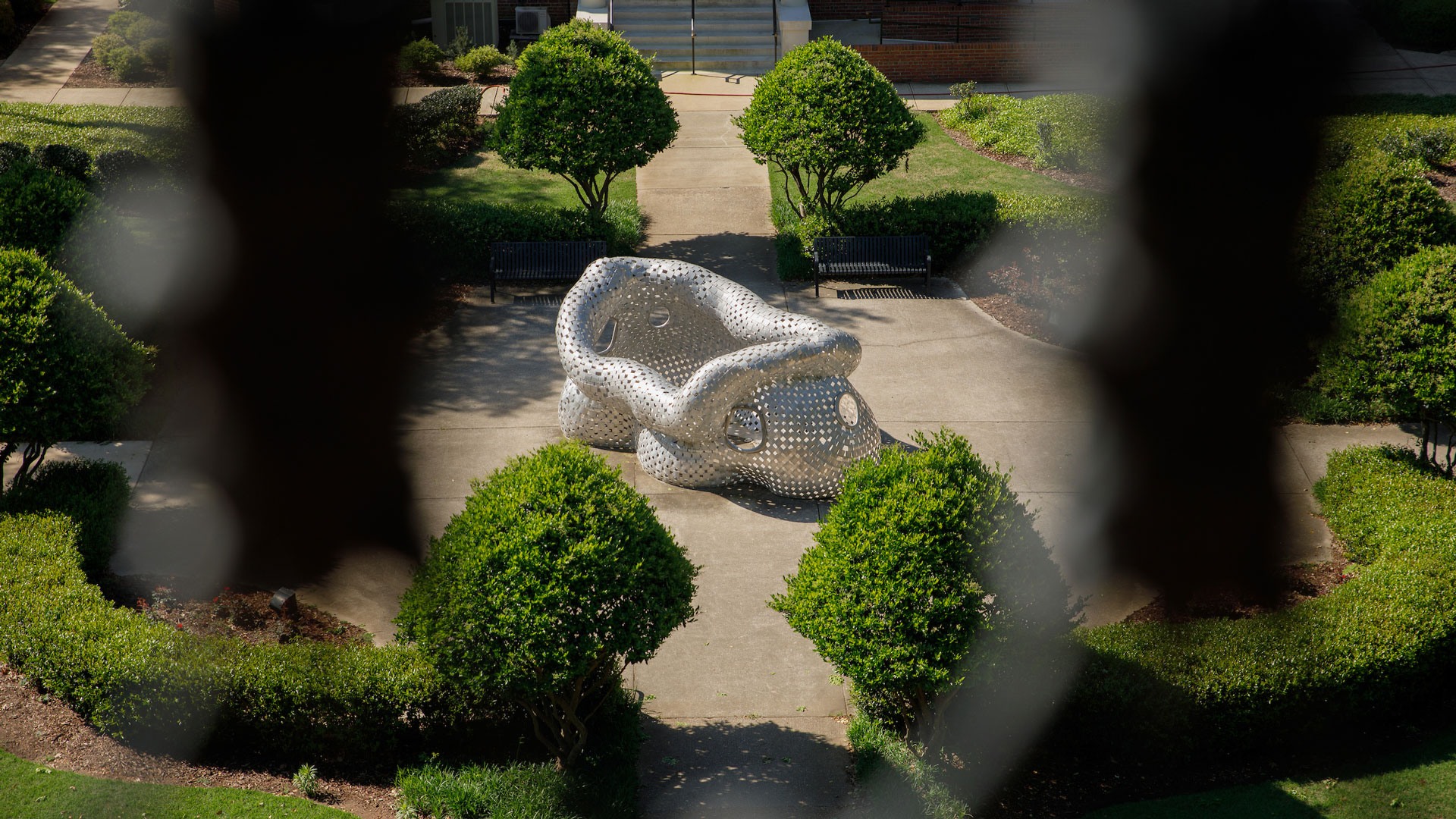 photograph of a silver metallic sculpture at the center of the Woods Quad taken from the balcony