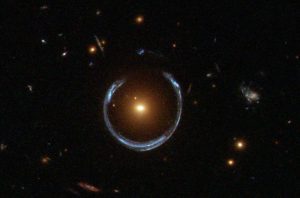 An image of space with a bright dot in the center surrounded by a blue horseshoe of light.
