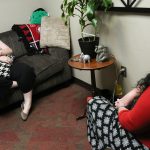 a woman sits on a couch talking to a counselor at the UA Counseling Center