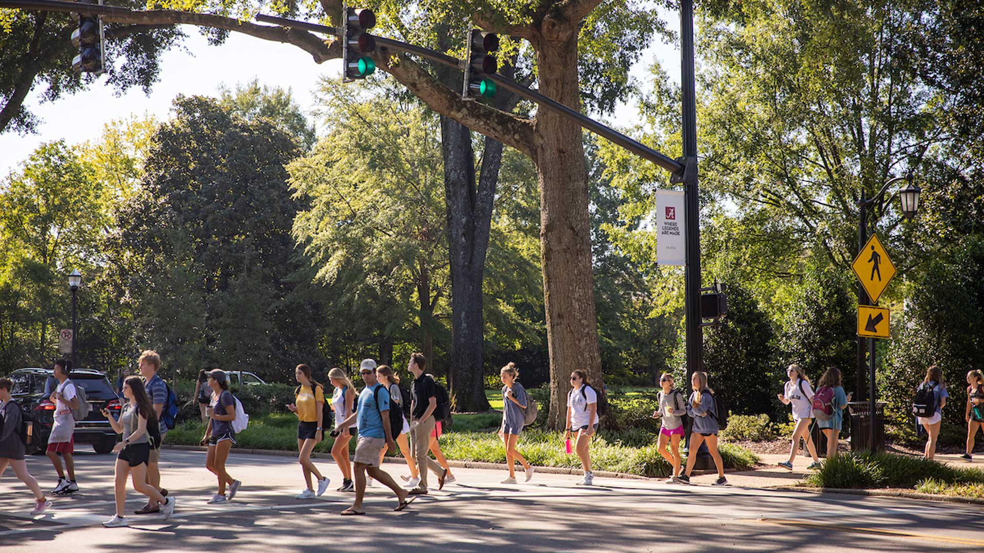 Students walk across the street on a summer day.