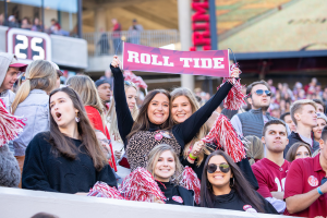 Students at an Alabama football game hold up a sign that says Roll Tide.