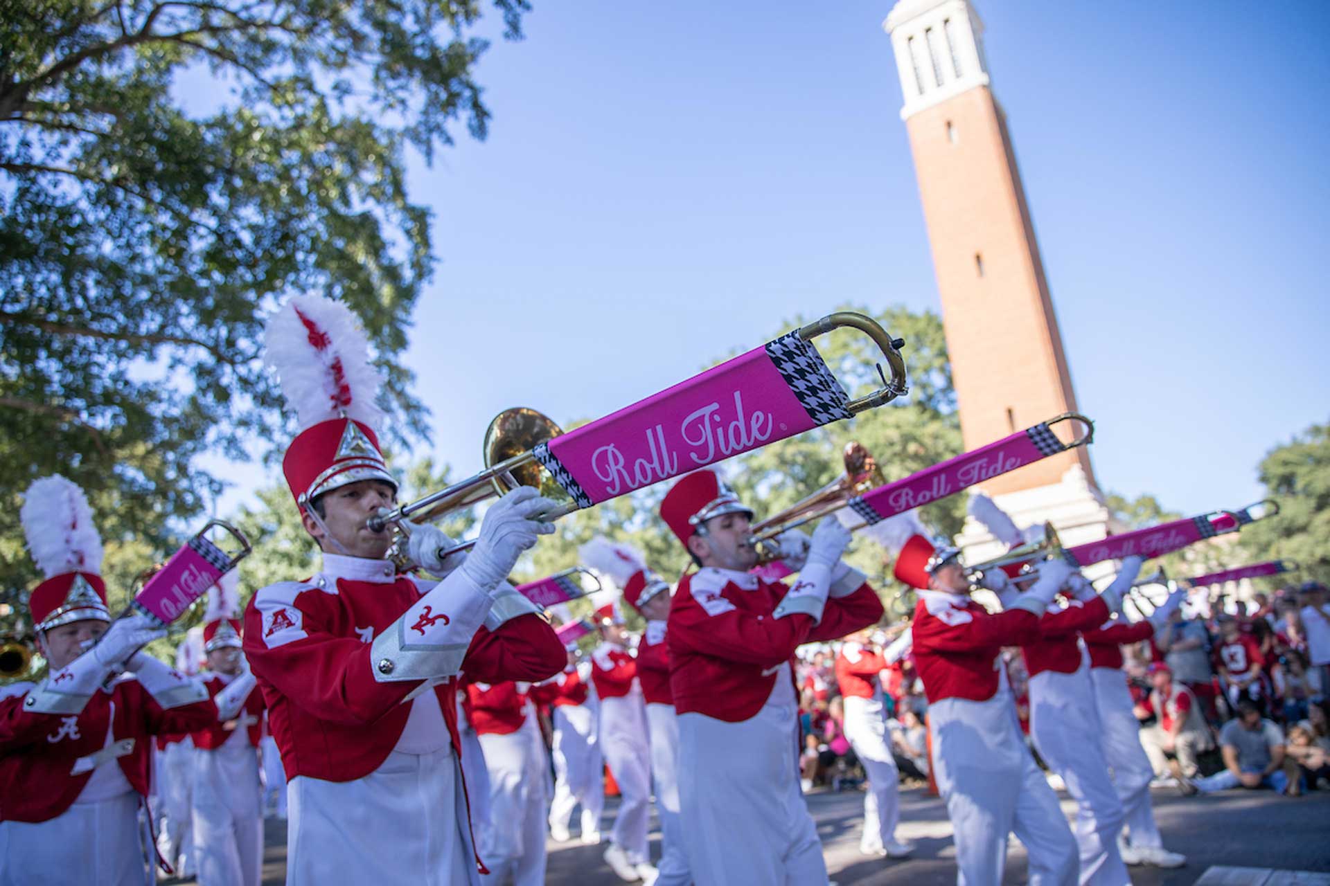 Several people dressed in marching band gear play instruments while in the homecoming parade.