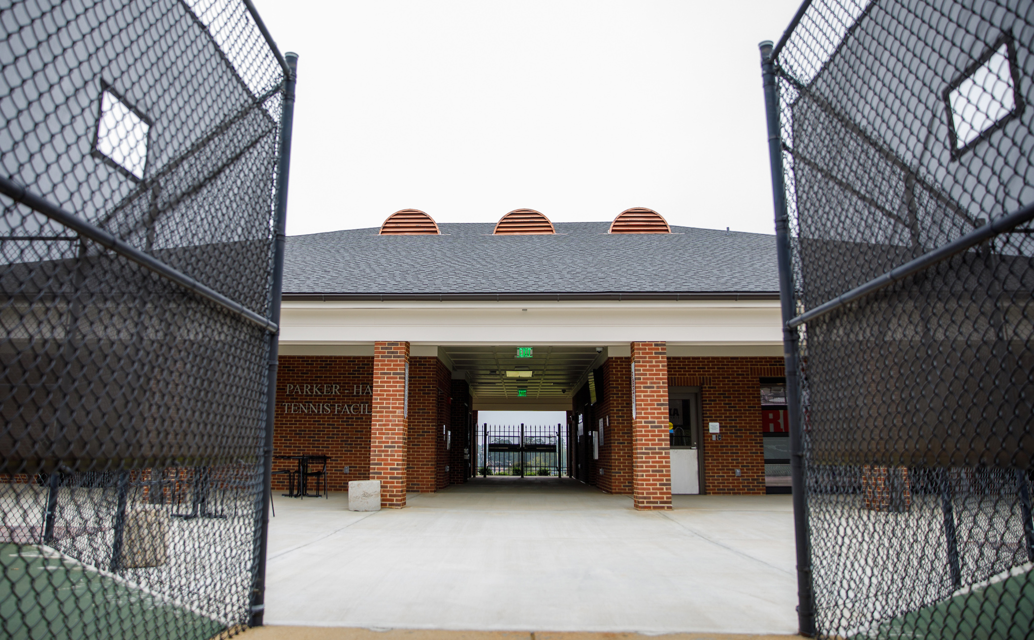 The exterior of the Parker Haun Tennis Facility between two tennis courts