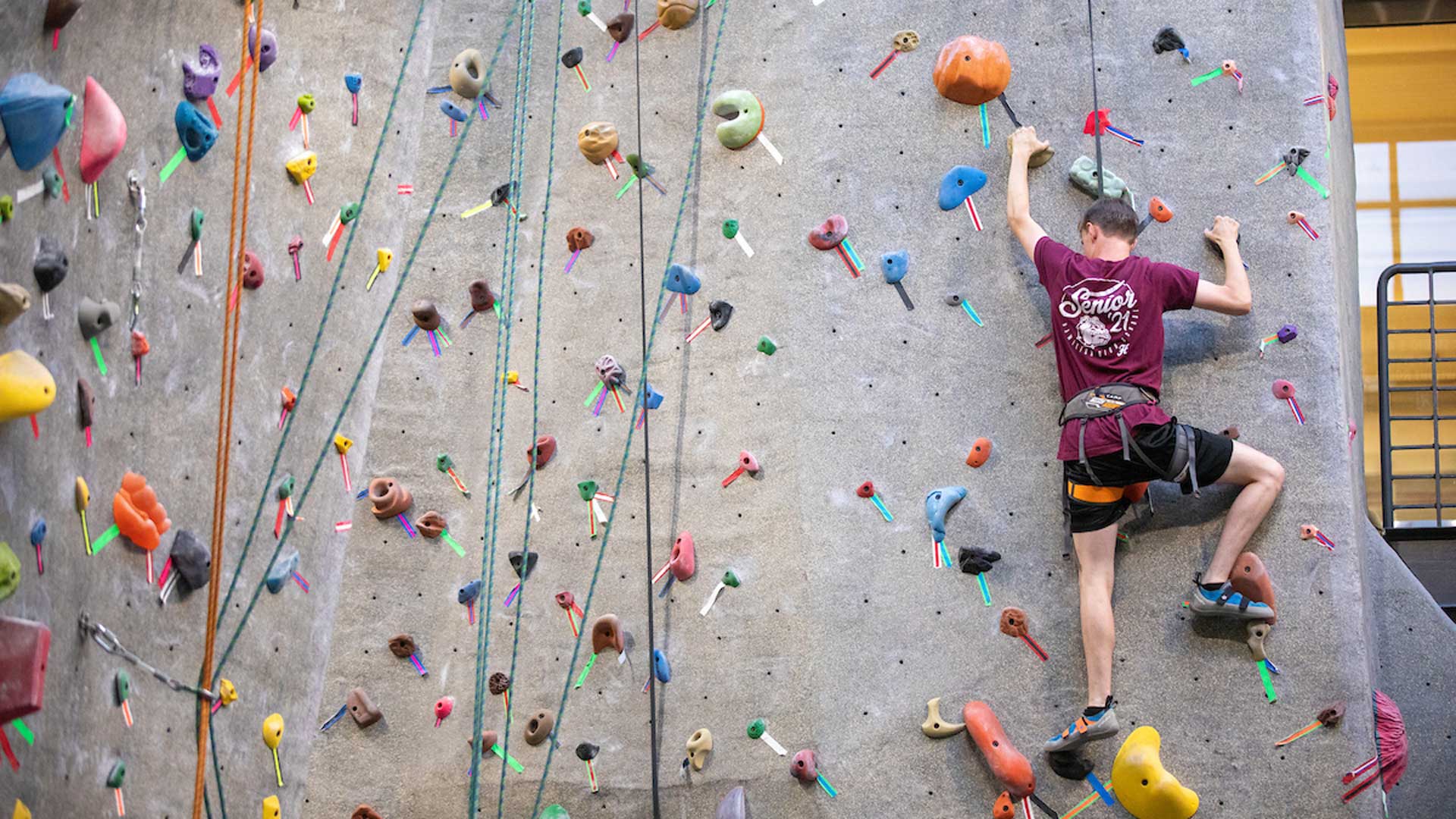 A student climbs up a rock climbing wall.