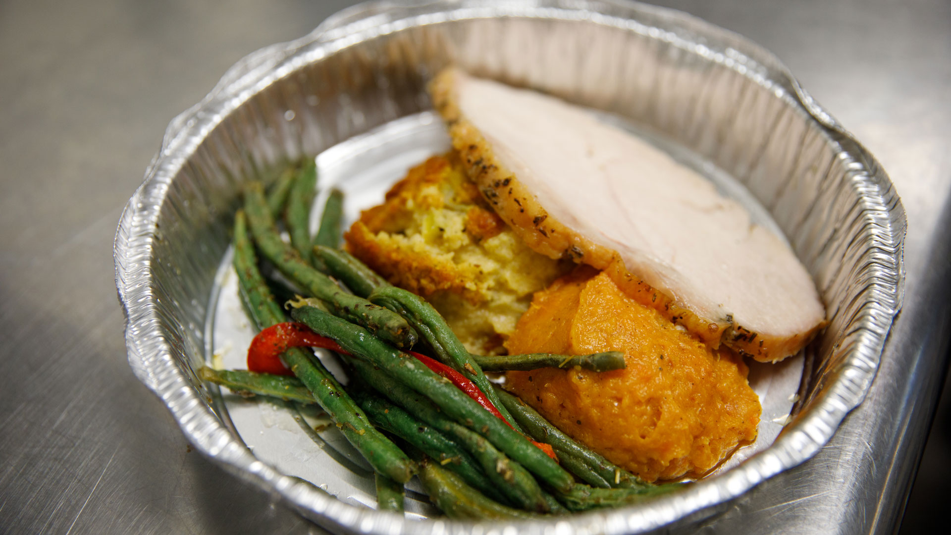 a aluminum tin of turkey, green beans and dressing