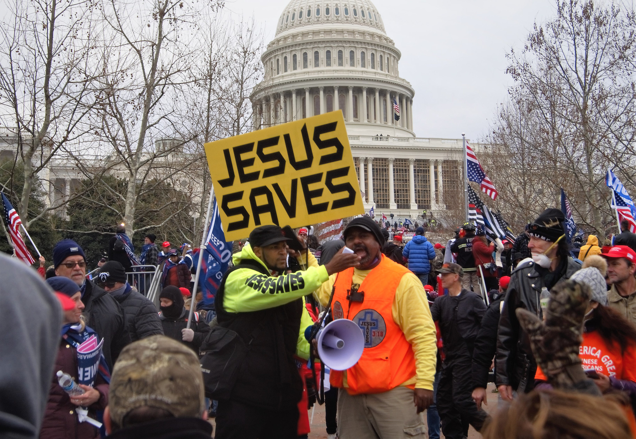 A crowd I front of the capitol with a sign that says Jesus Saves. 