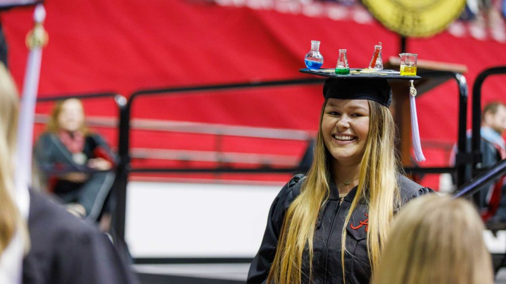 A girl smiles while wearing a cap and gown.