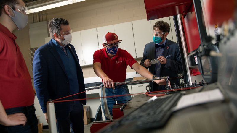 University of Alabama researchers discuss a project around a machine.