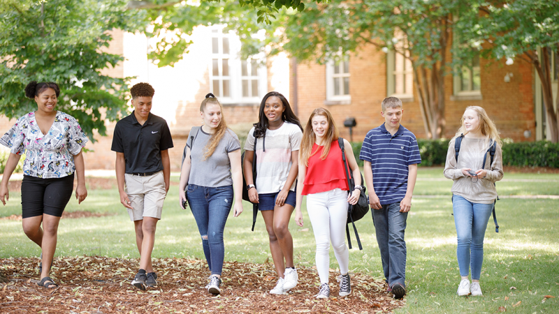 a group of high school-age students walking across the UA campus