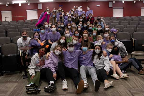 Students wearing masks are grouped together posing for a picture. Approximately 60 students in total.