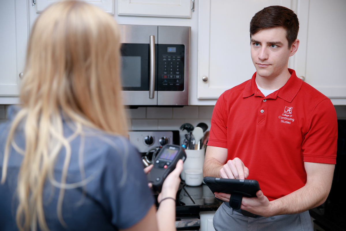A man using a tablet computer discusses health hazards in a home kitchen.