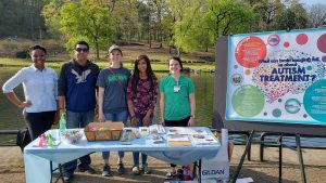a group of people stand behind a table to promote autism awareness and research