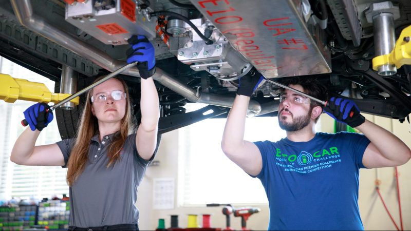 University of Alabama students work in an in a car garage.