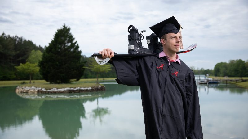 Sean Hunter posing in a graduation cap and gown while holding water skis over his shoulder