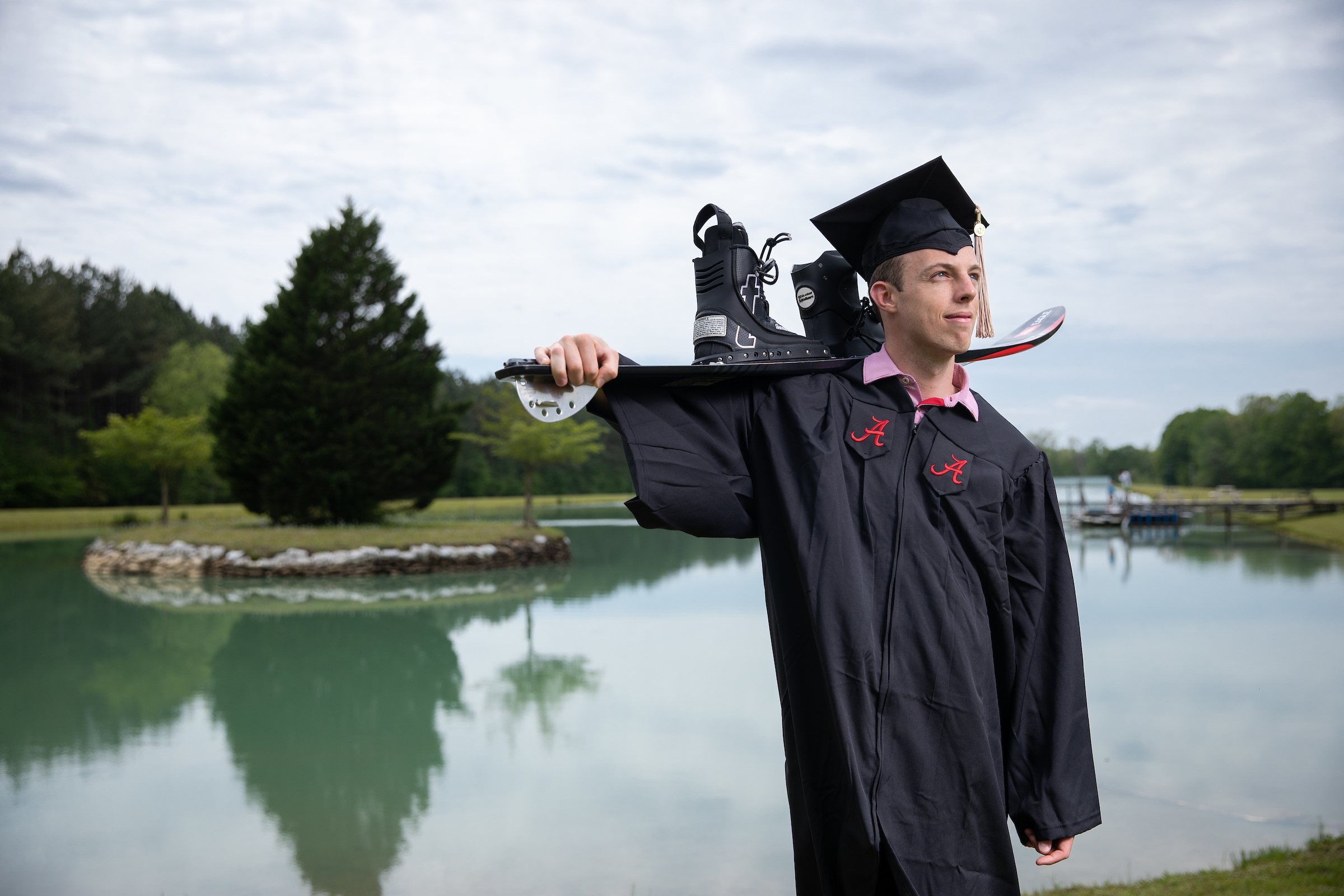 Sean Hunter posing in a graduation cap and gown while holding water skis over his shoulder