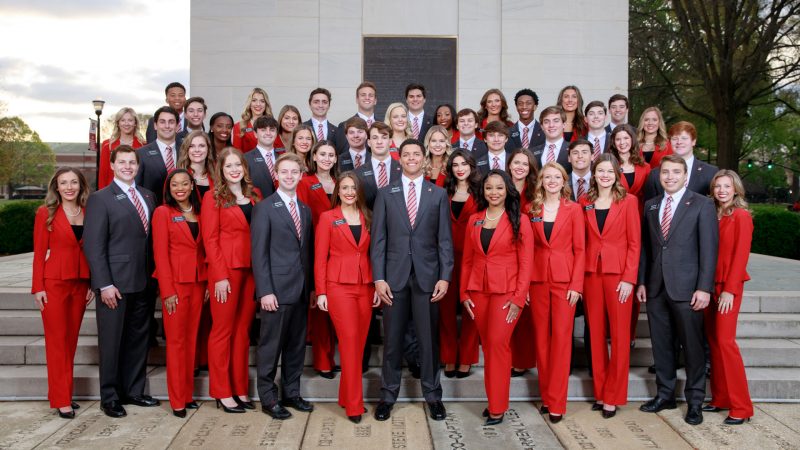 Member of the 2022-2023 class of Capstone Men and Women wearing their signature suits in front of Denny Chimes