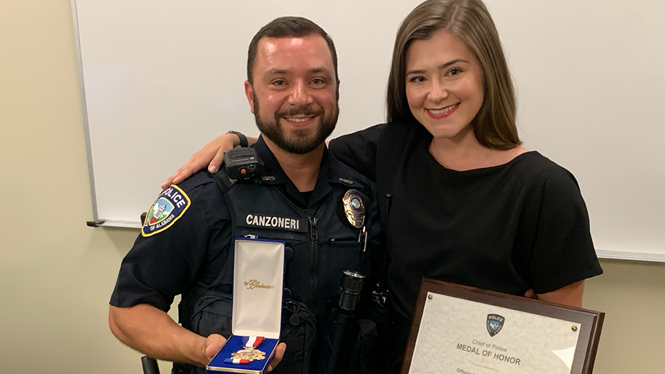 UAPD Officer Albert Canzoneri holds his medal of honor as he stands next to his wife, Shannon.