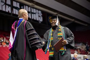 A graduate of The University of Alabama shakes the president's hand as he receives his degree.
