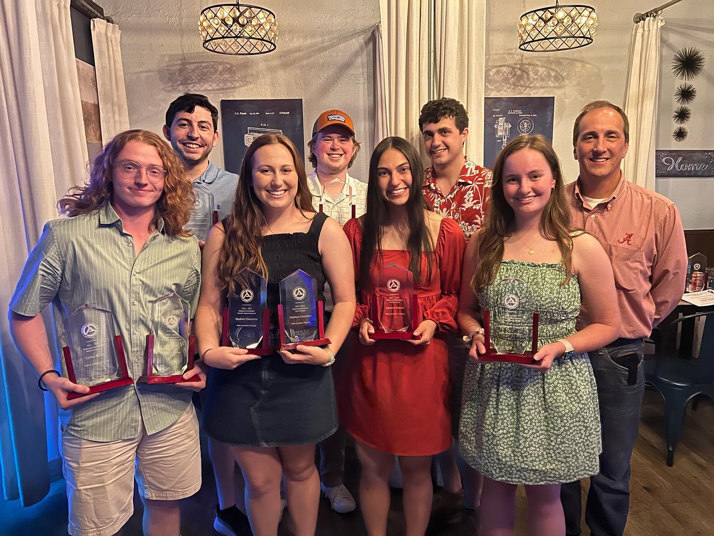 A group of people, some holding clear awards, pose for a photo in a restaurant.
