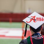 A degree candidate is wearing a cap that reads, "Roll Tide."