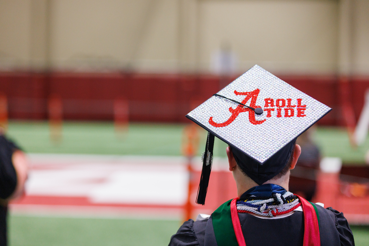 A degree candidate is wearing a cap that reads, "Roll Tide."