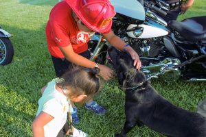 Two children pet a police dog.