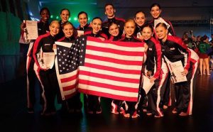 Hinojosa and her dance team holding an American flag after a competition