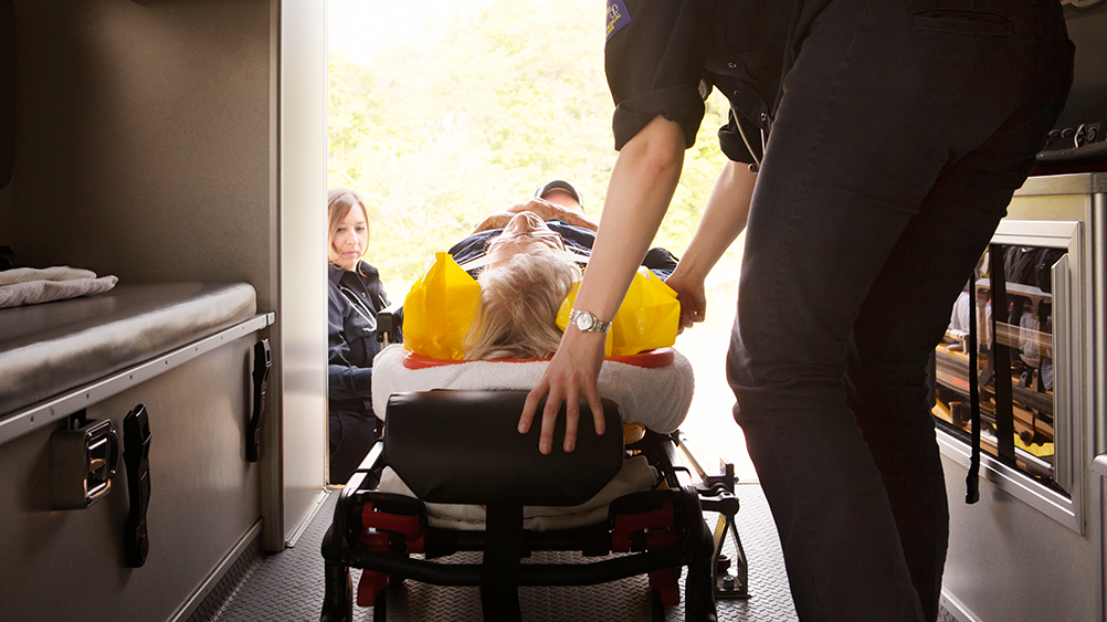 paramedics loading a person on a gurney into an ambulance